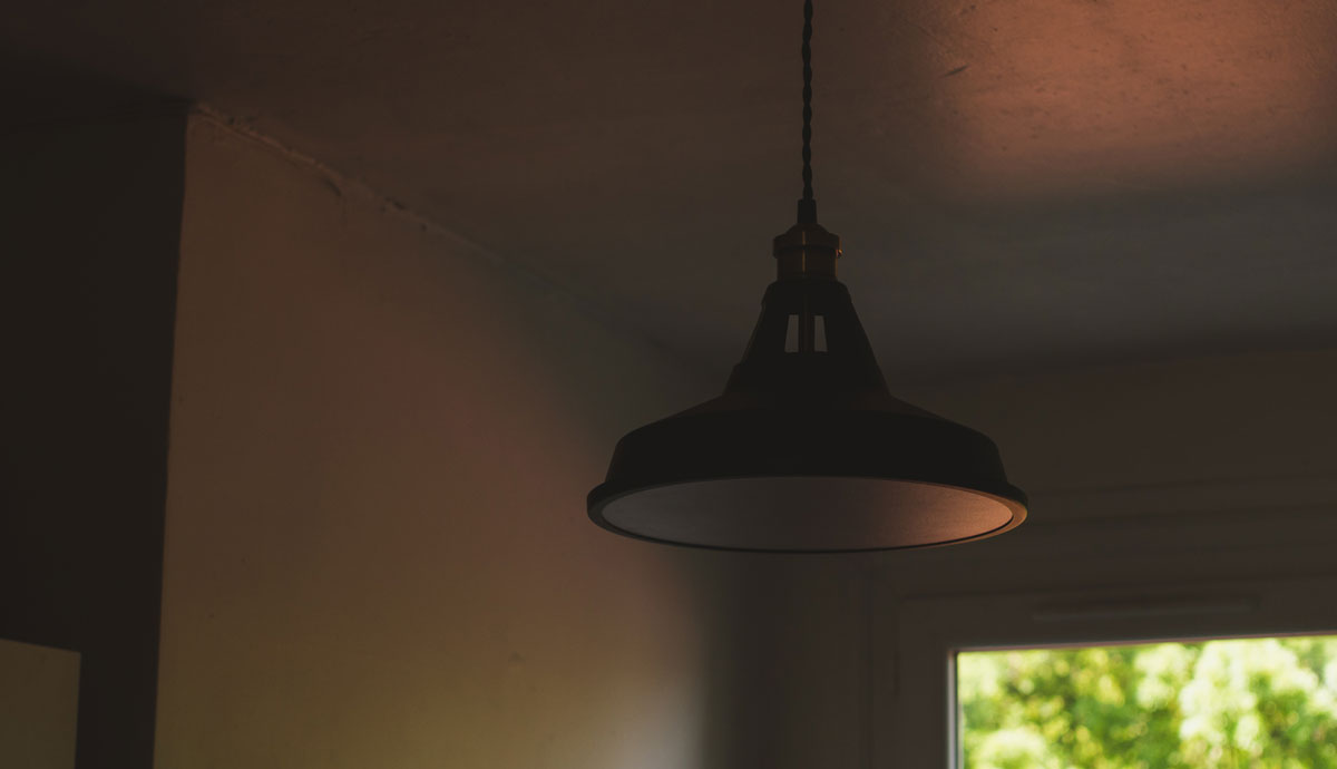 Ceiling mounted lamp reflecting an orange evening light coming from a nearby window